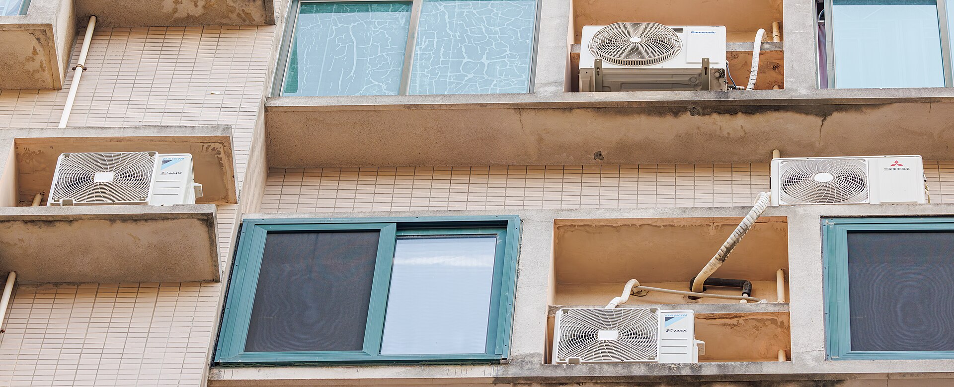 Rows of real outdoor air-conditioning units installed beside a building